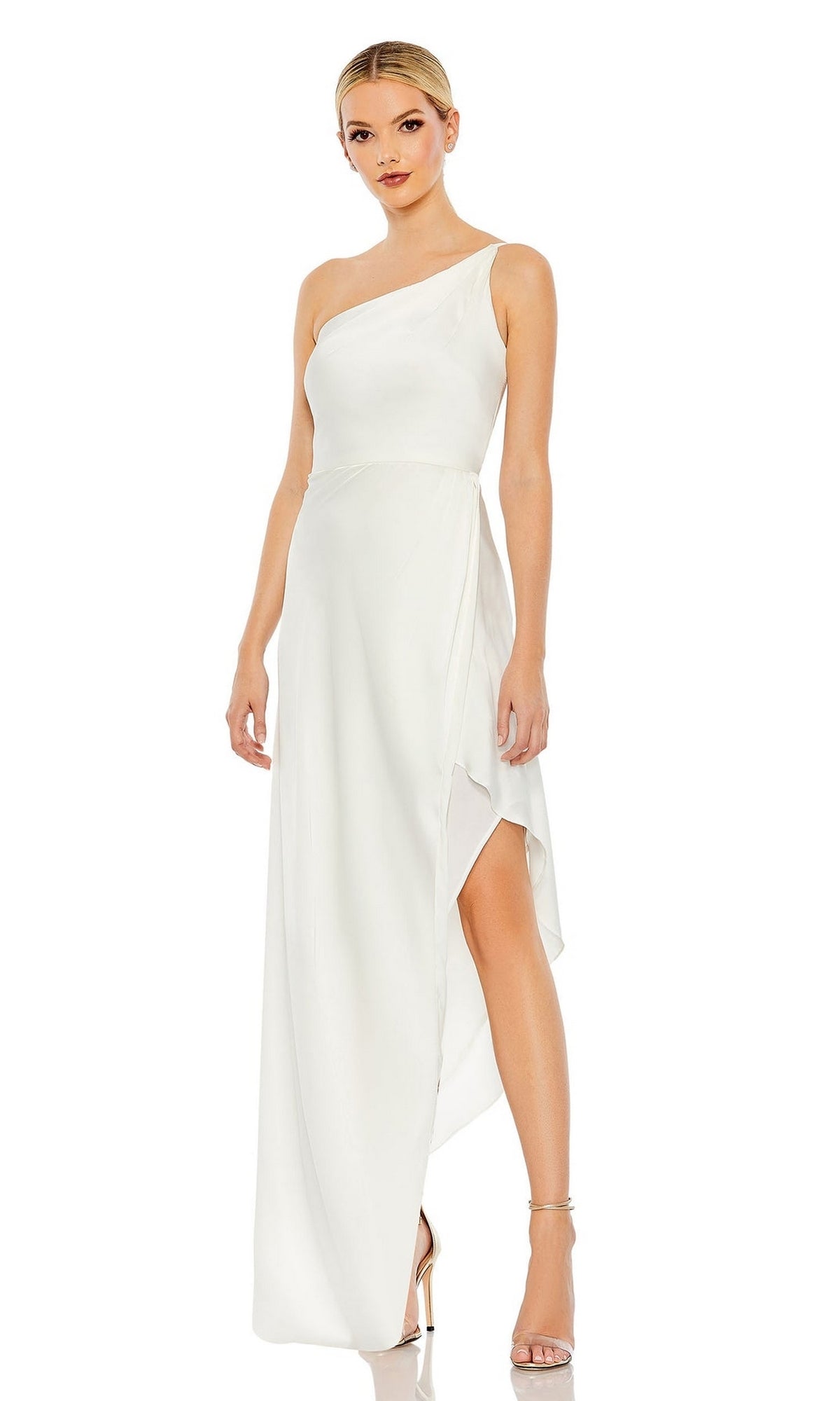 A woman wears the Mac Duggal 70177 High-Low Wedding Guest Dress, a white one-shoulder style with an asymmetrical hem, paired with strappy heels against a plain background.